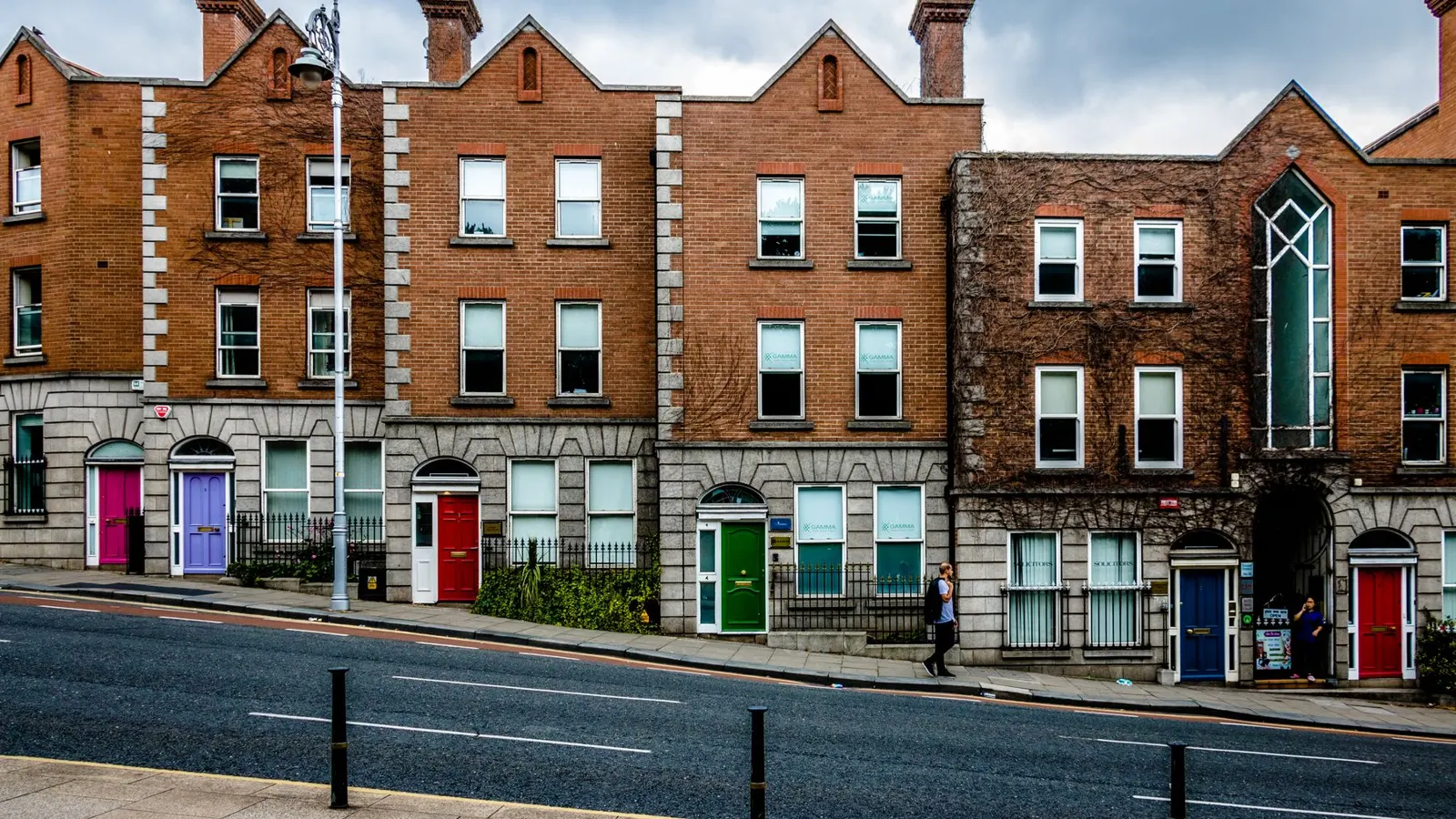 Red-brick Victorian terrace with brightly painted doors on a Dublin road