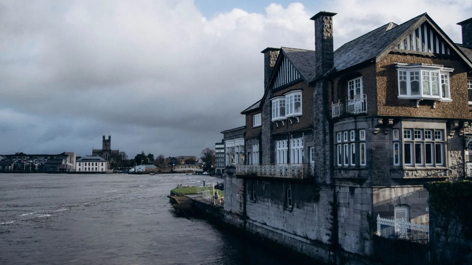 Old stone houses on the bank of the River Shannon in Limerick under grey cloud