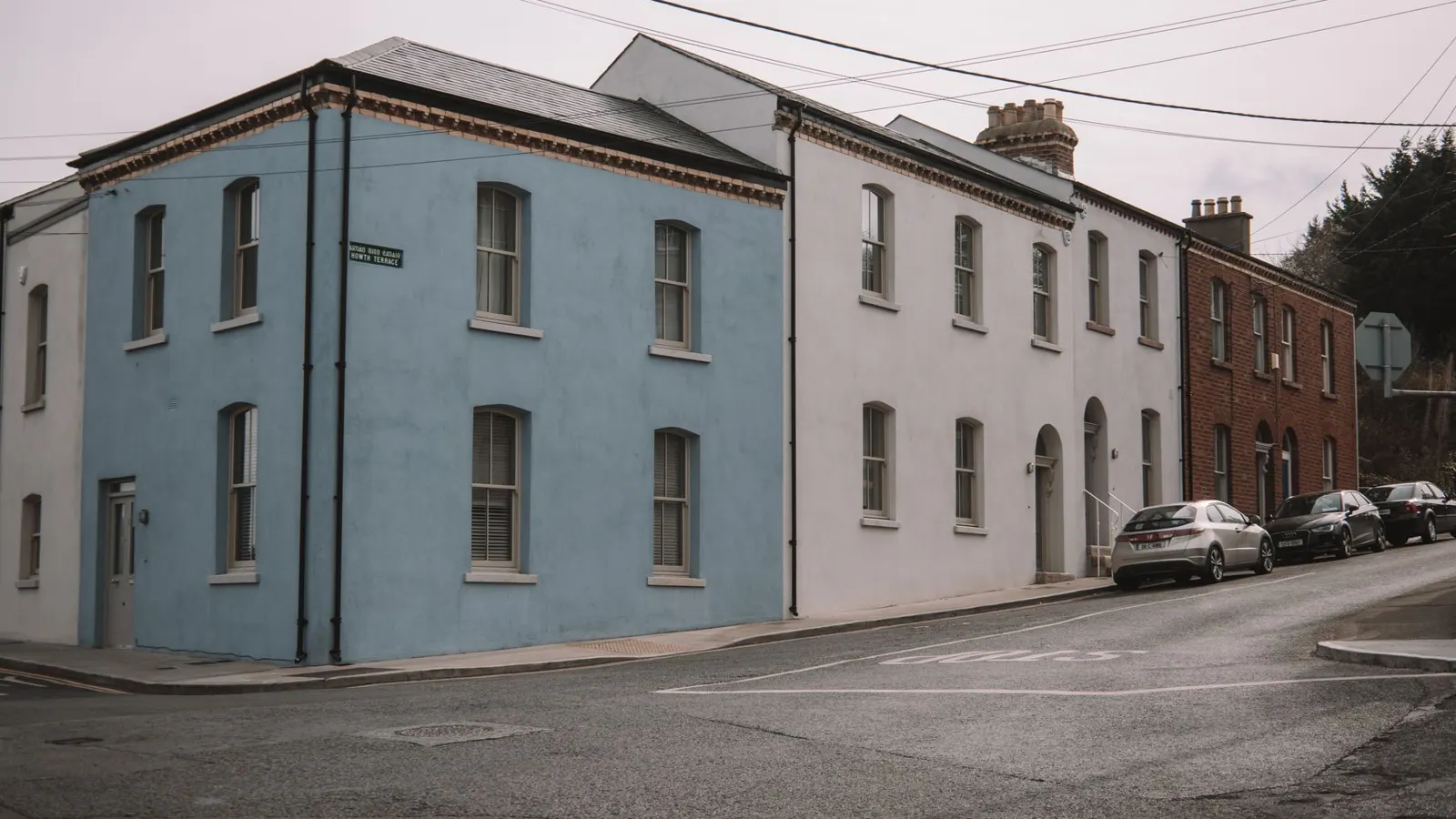 A pale blue corner house and brick terrace on a quiet Dublin street